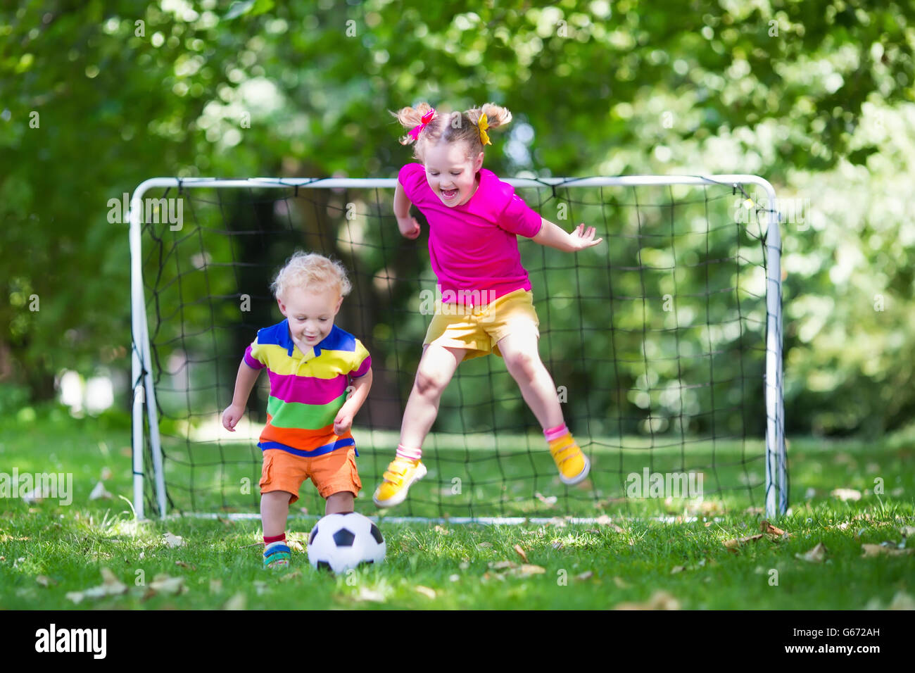 Zwei glückliche Kinder spielen Fußball im Freien im Schulhof. Kinder spielen Fußball. Aktiv Sport für Vorschulkind. Stockfoto