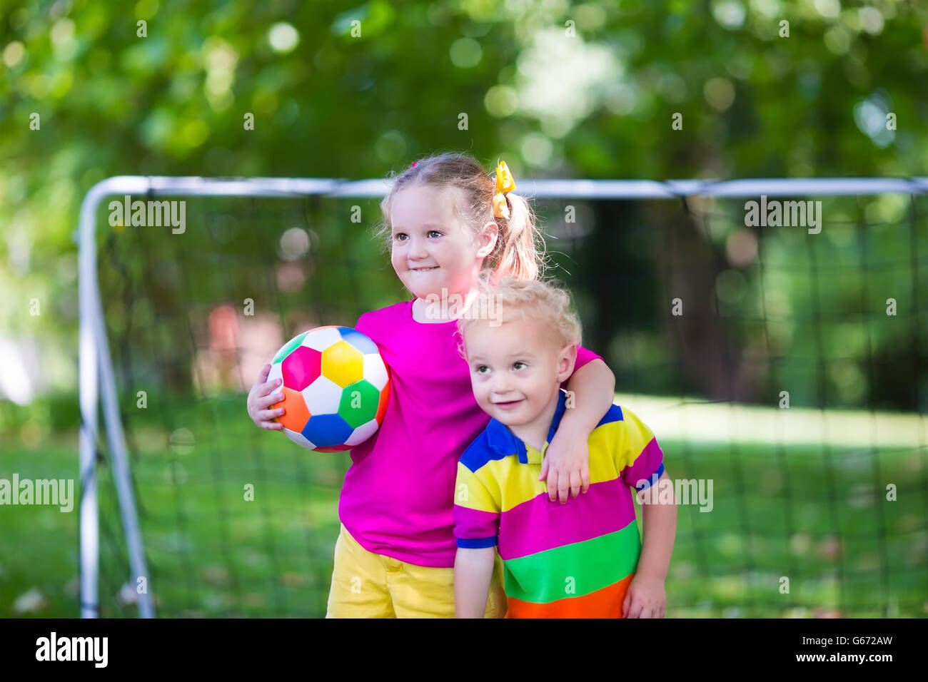 Zwei glückliche Kinder spielen Fußball im Freien im Schulhof. Kinder spielen Fußball. Aktiv Sport für Vorschulkind. Stockfoto