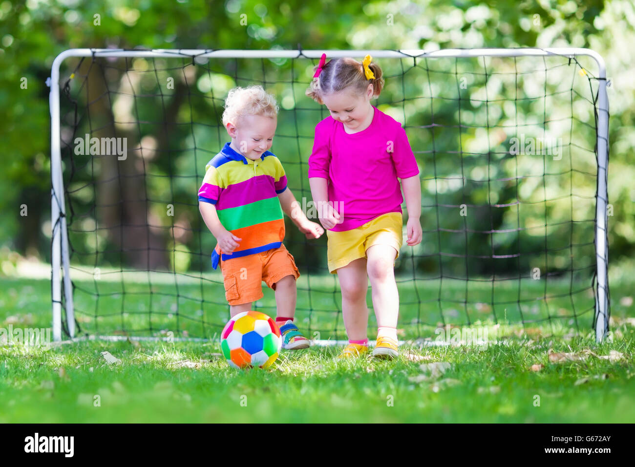 Zwei glückliche Kinder spielen Fußball im Freien im Schulhof. Kinder spielen Fußball. Aktiv Sport für Vorschulkind. Stockfoto