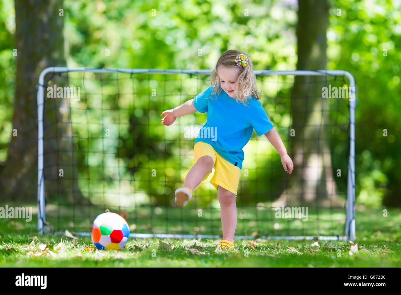 Zwei glückliche Kinder spielen Fußball im Freien im Schulhof. Kinder spielen Fußball. Aktiv Sport für Vorschulkind. Stockfoto