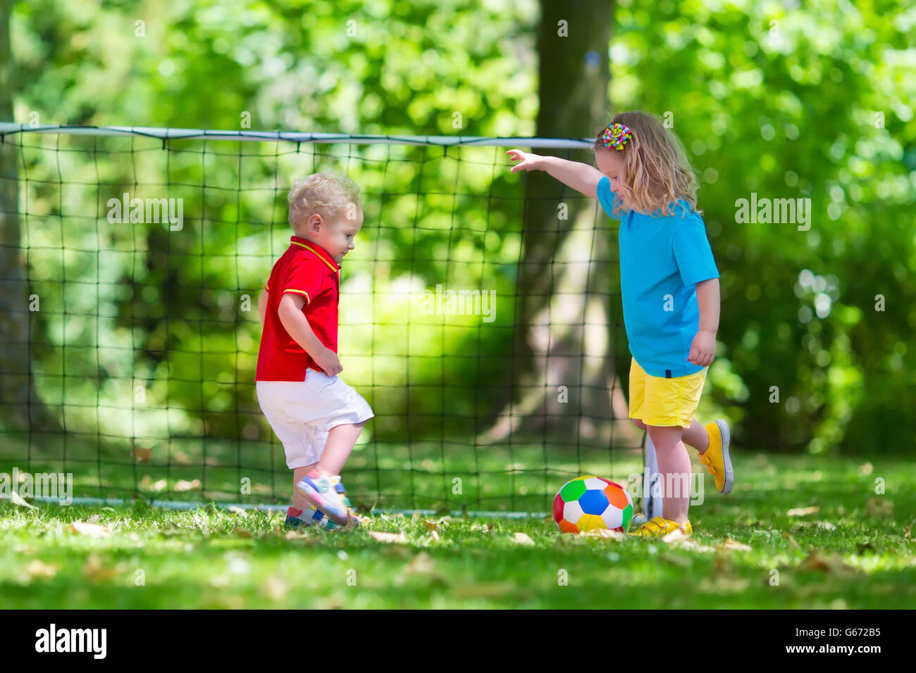 Zwei glückliche Kinder spielen Fußball im Freien im Schulhof. Kinder spielen Fußball. Aktiv Sport für Vorschulkind. Stockfoto