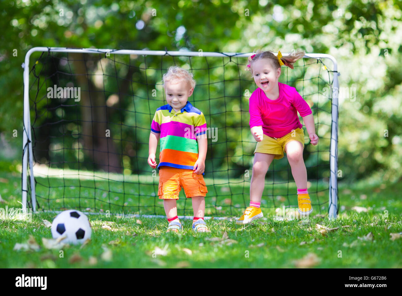 Zwei glückliche Kinder spielen Fußball im Freien im Schulhof. Kinder spielen Fußball. Aktiv Sport für Vorschulkind. Stockfoto