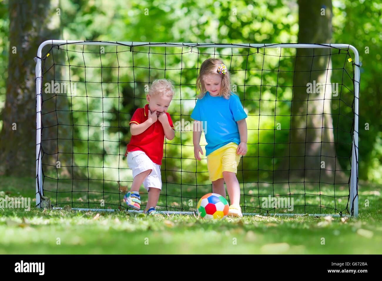 Zwei glückliche Kinder spielen Fußball im Freien im Schulhof. Kinder spielen Fußball. Aktiv Sport für Vorschulkind. Stockfoto
