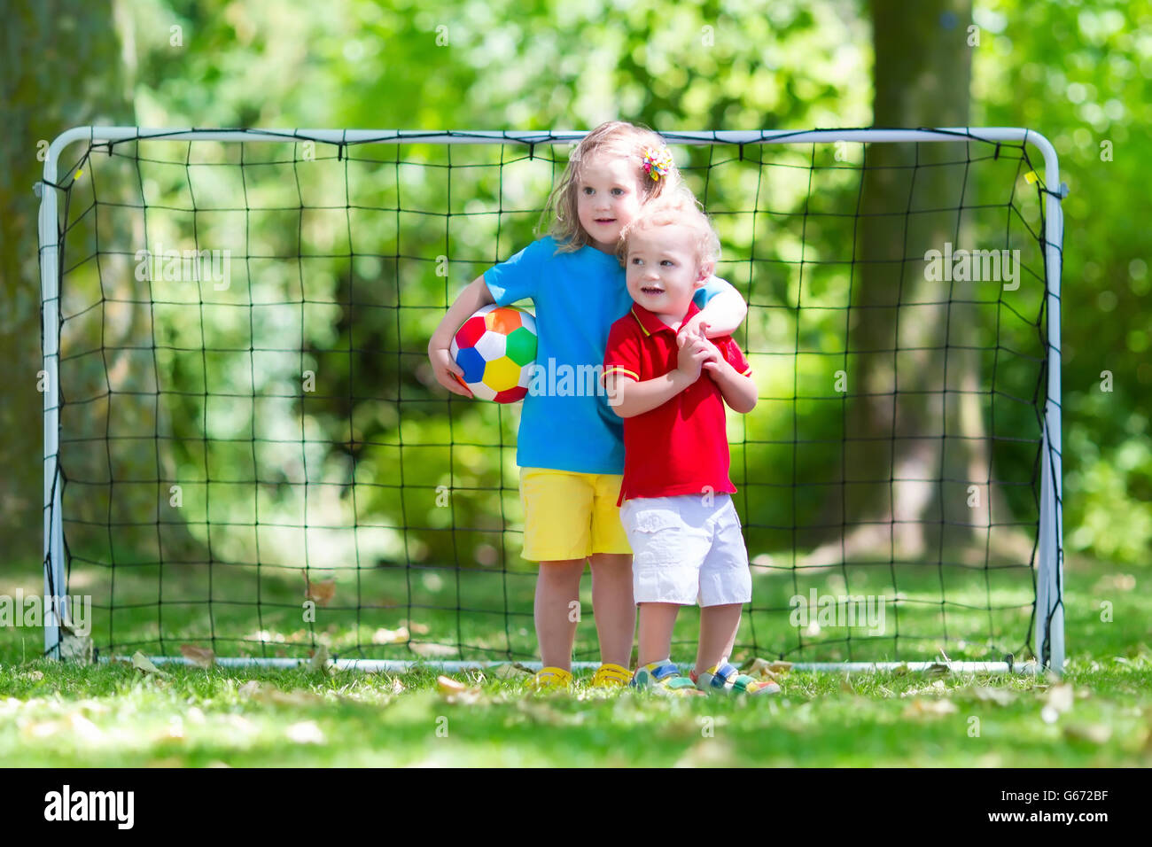 Zwei glückliche Kinder spielen Fußball im Freien im Schulhof. Kinder spielen Fußball. Aktiv Sport für Vorschulkind. Stockfoto