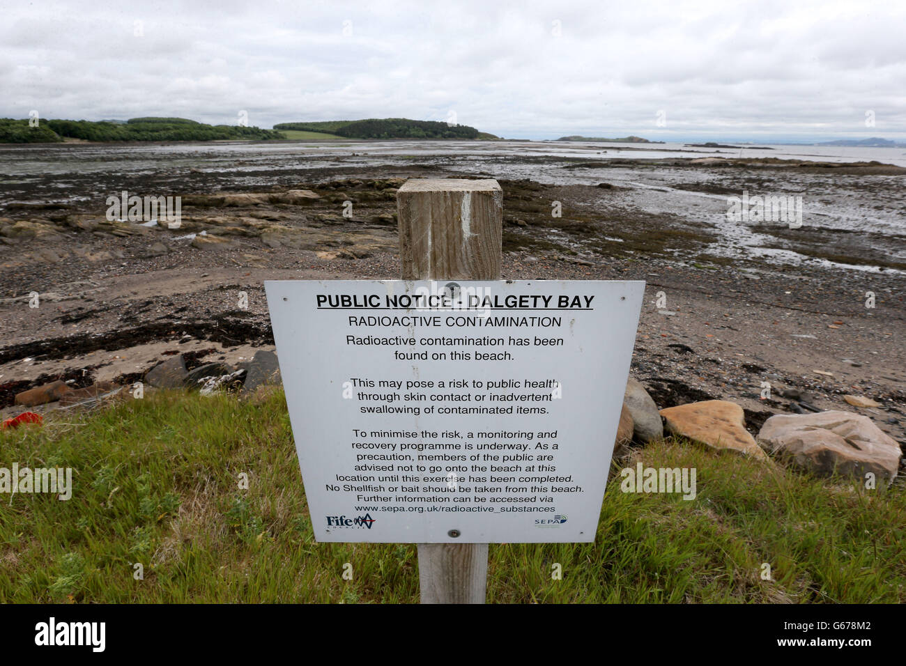 Ein Schild neben dem Strand von Dalgety Bay in Fife als ehemaliger Premierminister Gordon Brown hat das Verteidigungsministerium aufgefordert, die Sanierung des Strandes zu finanzieren, der durch Strahlung verschmutzt ist, nachdem eine Umweltbehörde die Regierungsabteilung als verantwortlich bezeichnet hat. Stockfoto