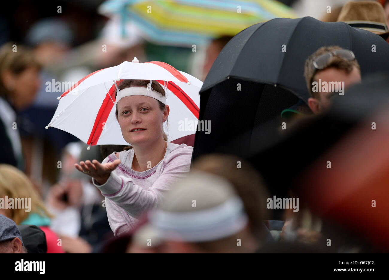 Am vierten Tag der Wimbledon Championships am All England Lawn Tennis und Croquet Club in Wimbledon schützen sich Fans vor dem Regen auf dem Platz zwei. Stockfoto