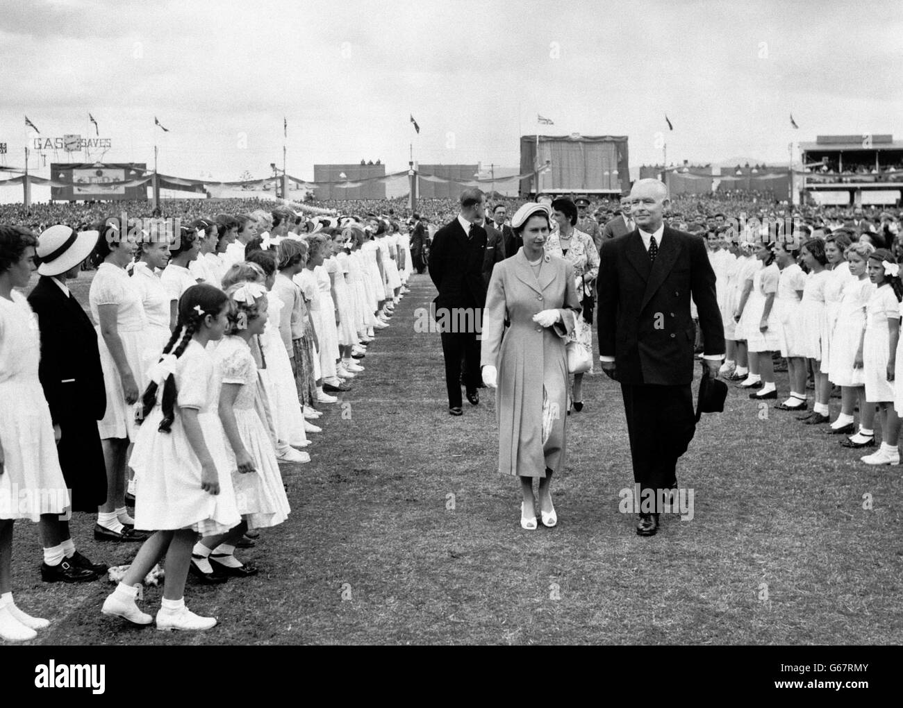 Weiß gekleidete Kinder flüchten zur Queen, während sie durch die Ehrenwache geht, die für ihren Besuch bei der gigantischem Jugendtreffen am Wayside Oval, dem Adelaide Cricket Ground, Südaustralien, auftrat. Die Kundgebung war die größte ihrer Art, die während der Königlichen Tournee des Commonwealth stattfand. Stockfoto