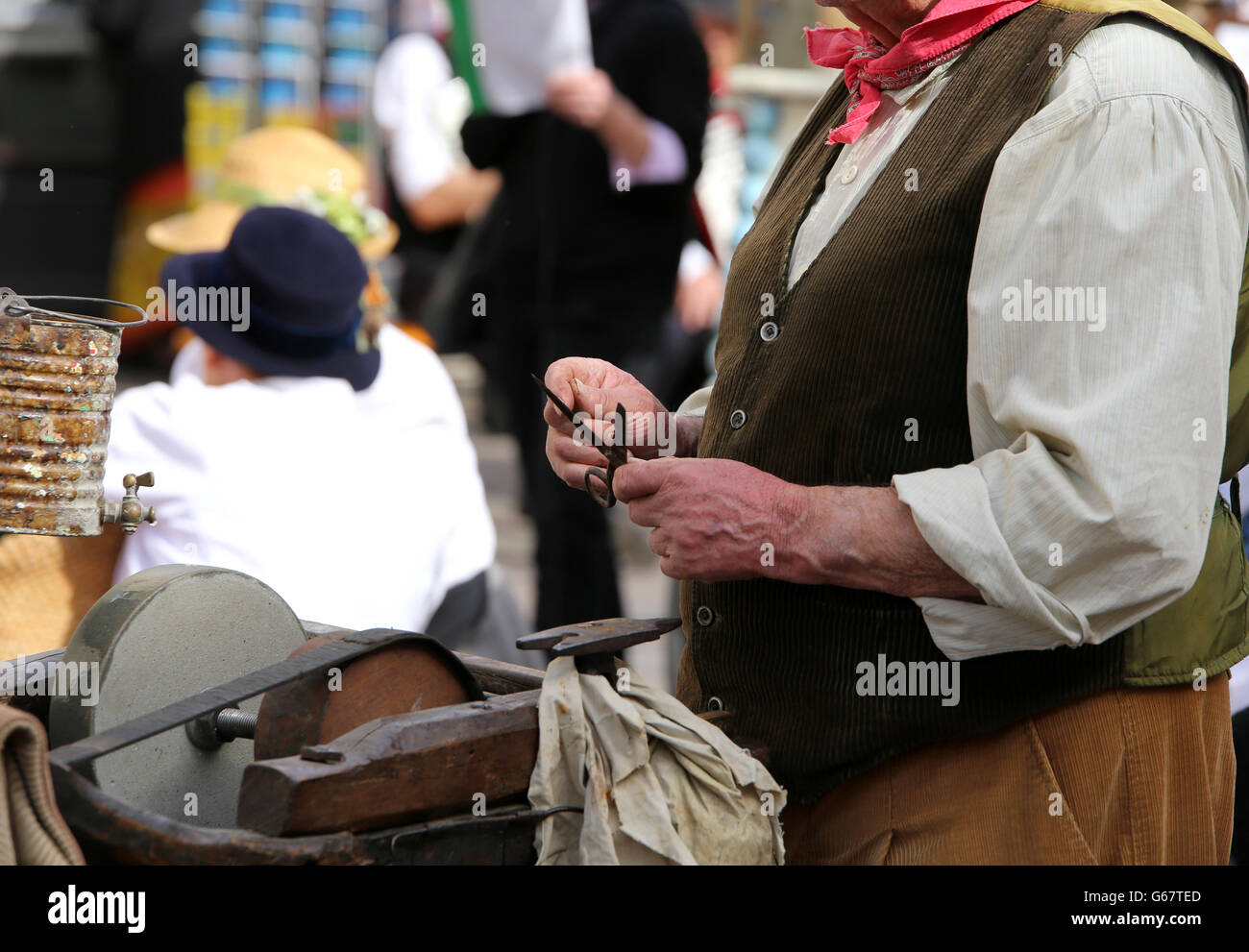 Seniro während schärft Messer in einem sehr alten Schleifstein Stockfoto