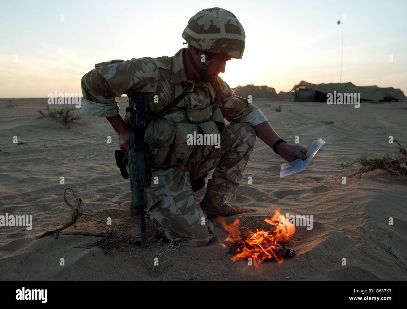 Ein Soldat des britischen 29 Commando Regiment Royal Artillery 'sanitises' sein Kit, indem er seine persönliche Post in der Kuwait-Wüste nahe der irakischen Grenze verbrennt. *..Truppen, die möglicherweise an zukünftigen Operationen beteiligt sind, desinfizieren ihre Ausrüstung, um keine Effekte einzuschließen, die dem Feind helfen könnten. Während sich die Streitkräfte in den Golfstaaten auf den Krieg zurüsten, wird US-Präsident Bush am Sonntag mit den britischen und spanischen Premierministern zusammentreffen, inmitten einer diplomatischen Sackgasse vor den Vereinten Nationen wegen der von den USA geführten Pläne zur Entwaffnung des Irak. Stockfoto