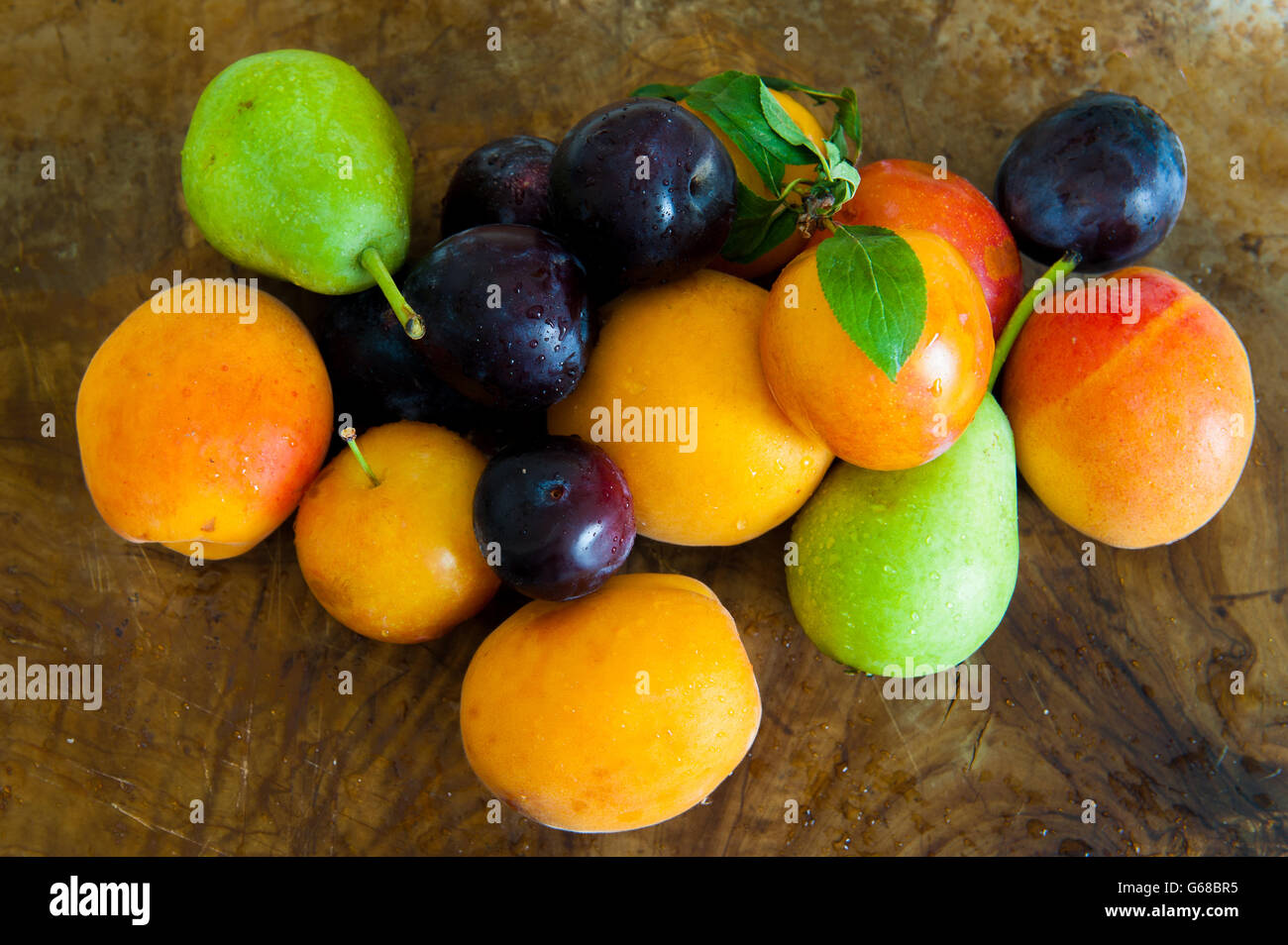 Haufen von Pflaume, Aprikose, Birne, bunte frische Saisonfrüchte auf hölzernen baclground Stockfoto