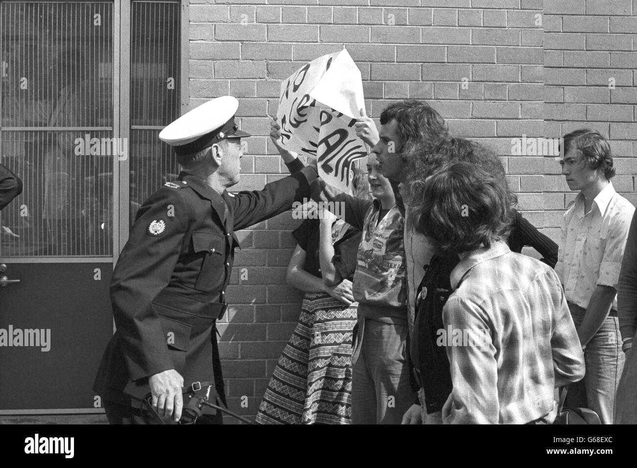 Ein Polizist schnappt einem Demonstranten vor dem Royal Women's Hospital in Melbourne ein Transparent, bevor die Queen während ihrer Silver Jubilee Tour of Australia zu Besuch kommt. Stockfoto