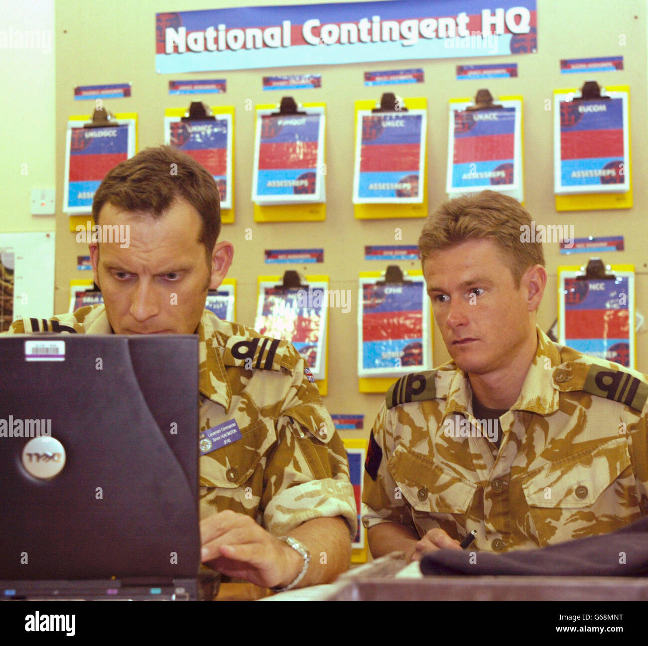 Britische Lt. Komm. Simon Huntington (L) arbeitet an einem Laptop-Computer, während ein unidentifizierter Militärangehörige bei einem Pressebesuch im British Operations Command Center in Camp als Sayliyah außerhalb von Doha, Katar, zuschaut. US-Präsident George W. * Bush begann den Countdown zum Krieg am Montagabend, in einer Rede, die Saddam 48 Stunden gab, um den Irak zu verlassen oder der Invasion von 280,000 Truppen in der für den Krieg ausgeregten Golfregion zu begegnen. Saddam am Dienstag verachtete das Ultimatum, sein Kabinett schwor, "eindringende Aggressoren abzuwehren. Stockfoto