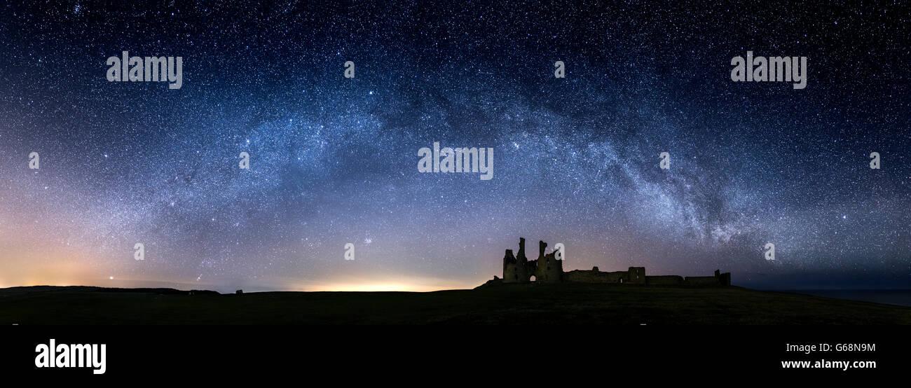 Die Milchstraße Lichtbögen über Dunstanburgh Castle in Northumberland UK Stockfoto