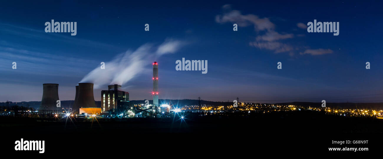 Rugeley Power Station in der Nacht mit den Straßenlaternen Rugeley Stadt funkeln im Hintergrund arbeiten. Stockfoto