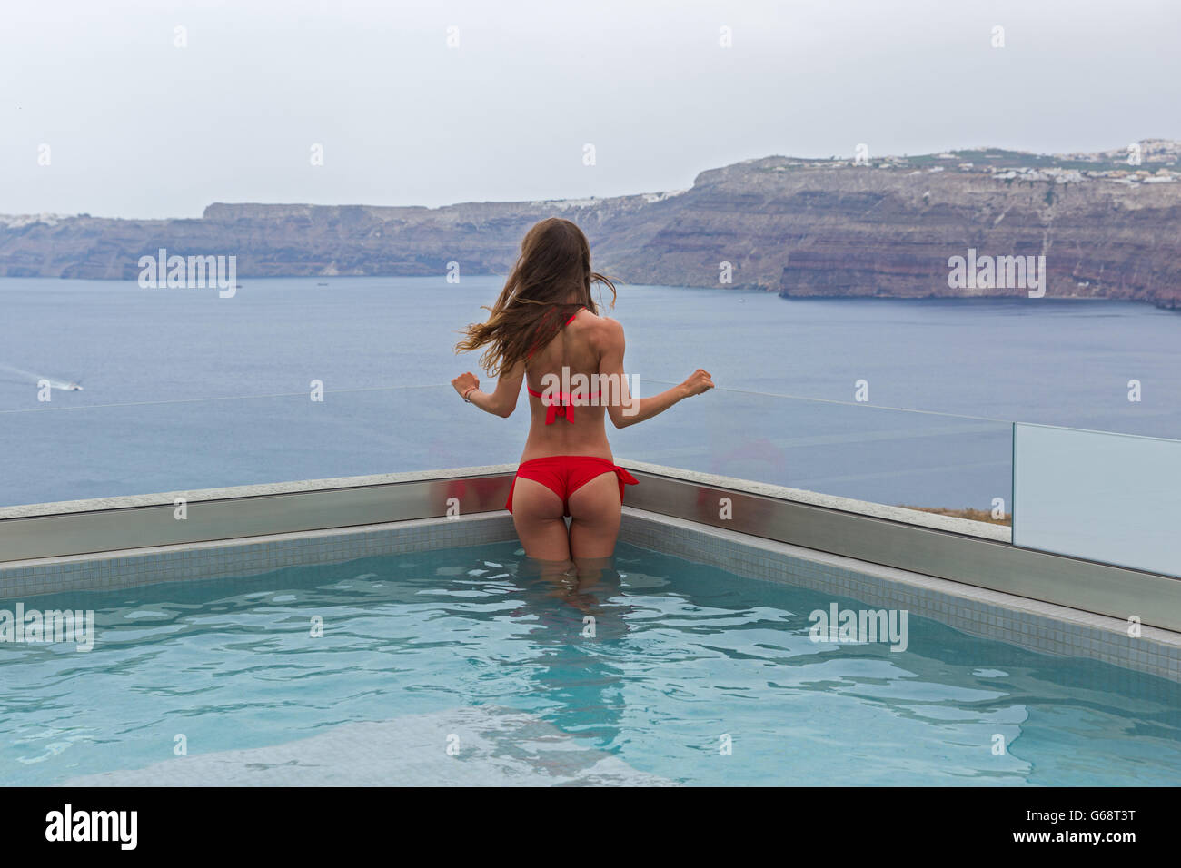 Junge Frau im Pool mit Blick auf das Meer Stockfoto