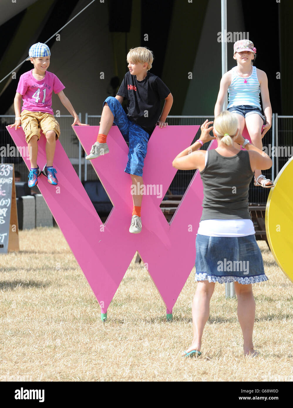 Womad Festival 2013. Kinder posieren für ein Foto auf einer Skulptur während des Womad Festivals 2013, das im Charlton Park in Wiltshire stattfand. Stockfoto