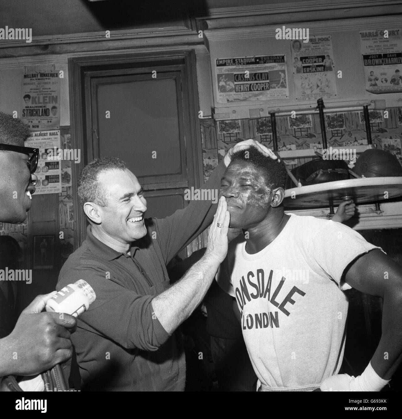 Gil Clancy bringt vor einer Trainingseinheit im Fitnessstudio Thomas A Beckett in London Mineralölgelee auf das Gesicht des Schweißergewichtsmeisters Emile Griffith. Stockfoto