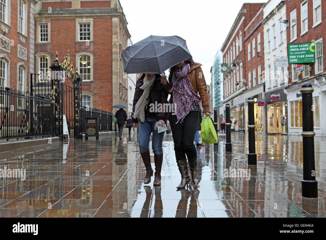 Zwei Frauen Einkaufen im Regen in der High Street in Worcester. Stockfoto