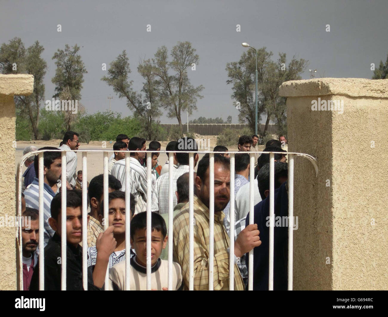 Die Einheimischen im südirakischen Hafen Umm Qasr stehen vor dem Gelände der britischen Streitkräfte in der Stadt. Trotz angeblicher Ängste vor dem Saddam-Regime beginnen sich immer mehr zu melden, um mit den Soldaten zu sprechen. * aber Oberst Steve Cox, der stellvertretende Kommandeur der 3 Commando Brigade, Royal Marines, Der als Militärbürgermeister bezeichnet wurde, sagte, dass die ehemaligen führenden Persönlichkeiten von Umm Qasr, alle Mitglieder der Baath-Partei, immer noch versuchen, die Einheimischen aus der Ferne einzuschüchtern und sie zu erschrecken, nicht zusammenzuarbeiten. Stockfoto