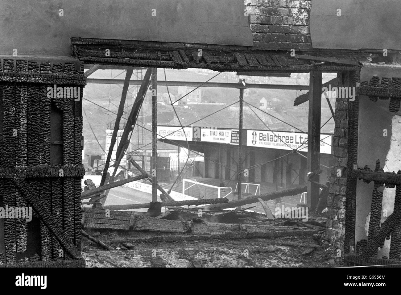 Der Rauch steigt immer noch von den verkohlten Resten der Haupttribüne auf dem Fußballplatz Valley Parade, nachdem der Brand, der über 50 Tote und mehr als 200 Verletzte hinterließ, unter Kontrolle gebracht wurde. Das Feuer fegte den gepackten Stand kurz vor der Halbzeit als Division Three Champions Bradford City spielte Lincoln City im letzten Spiel der Saison. Stockfoto