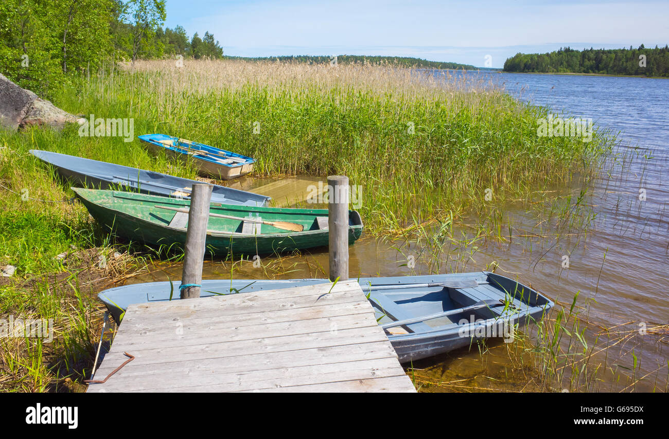 Kleine Ruderboote lag an der Küste noch See in der Nähe von hölzernen pier Stockfoto