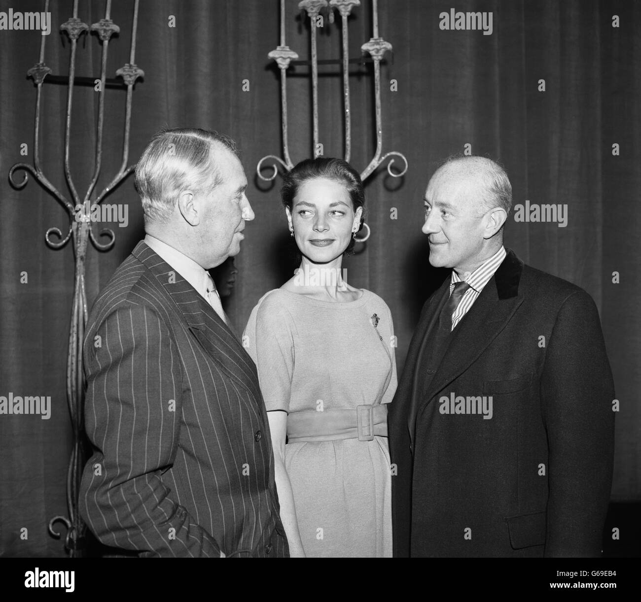 Maurice Chevalier (links) spricht mit Lauren Bacall und Alec Guinness bei der Probe für die Royal Film Performance im Empire Theatre am Leicester Square, London. Stockfoto