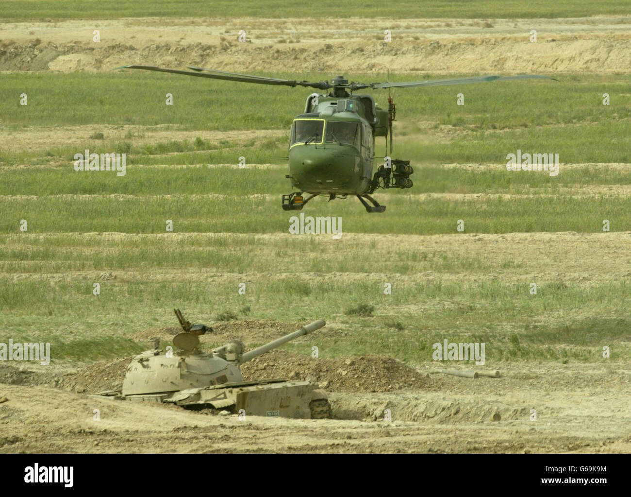 Ein Mark 7 Lynx Hubschrauber von 3 Reg Army Air Corps, 16 Air Assault Brigade auf einer Kampfpatrouille, mit SCHLEPPRAKETEN, fliegt über einem zerstörten irakischen T55 Panzer, südlich von Al Qurnah. Stockfoto