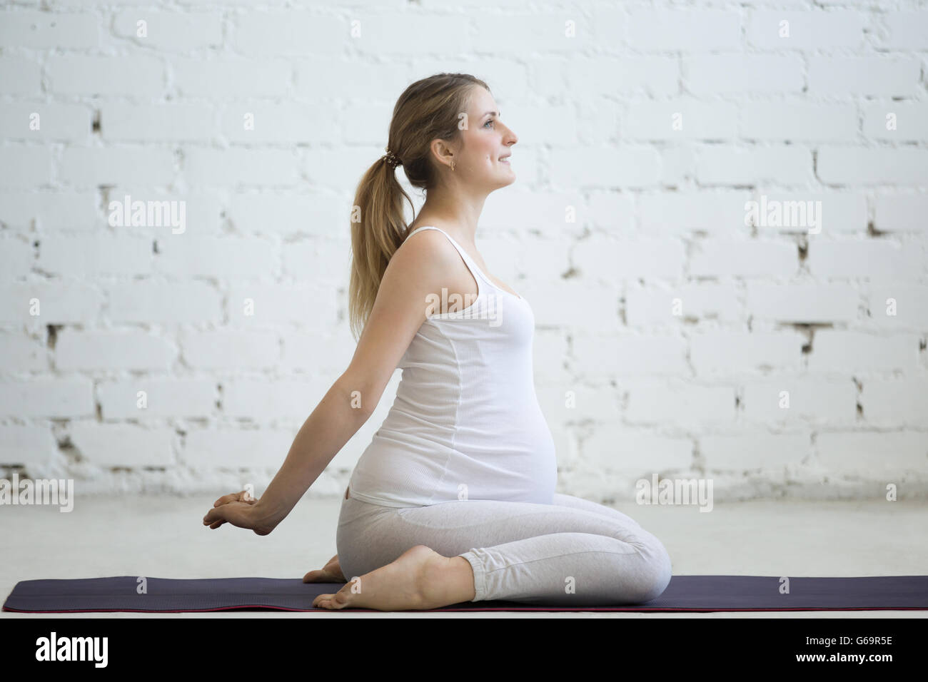 Schwangerschaft-Yoga und Fitness. Porträt des jungen schwangeren Yoga Modell Training im Loft. Schwangere Fitness Person lächelt Weile Stockfoto