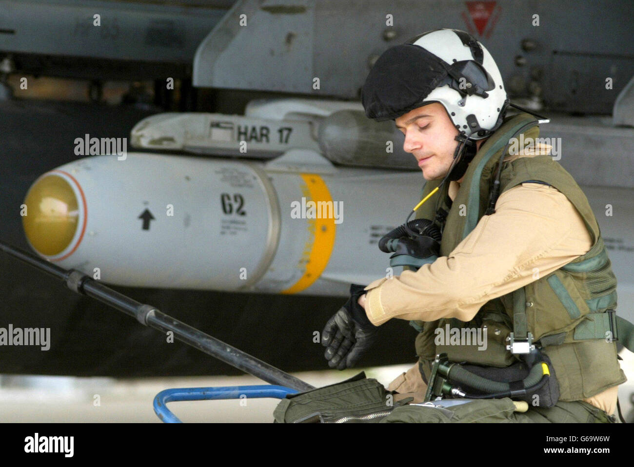 Der britische Pilot Flt LT Paul Francis überprüft seine Uhr, während er neben dem Flügel seines Harrier GR7 sitzt, bewaffnet mit einer Maverick-Rakete, an einer Basis in Kuwait. Das US-Zentralkommando sagte am Samstag, dass es keine "Pause" bei militärischen Operationen geben würde, um den irakischen Präsidenten Saddam Hussein zu stürzen. Stockfoto