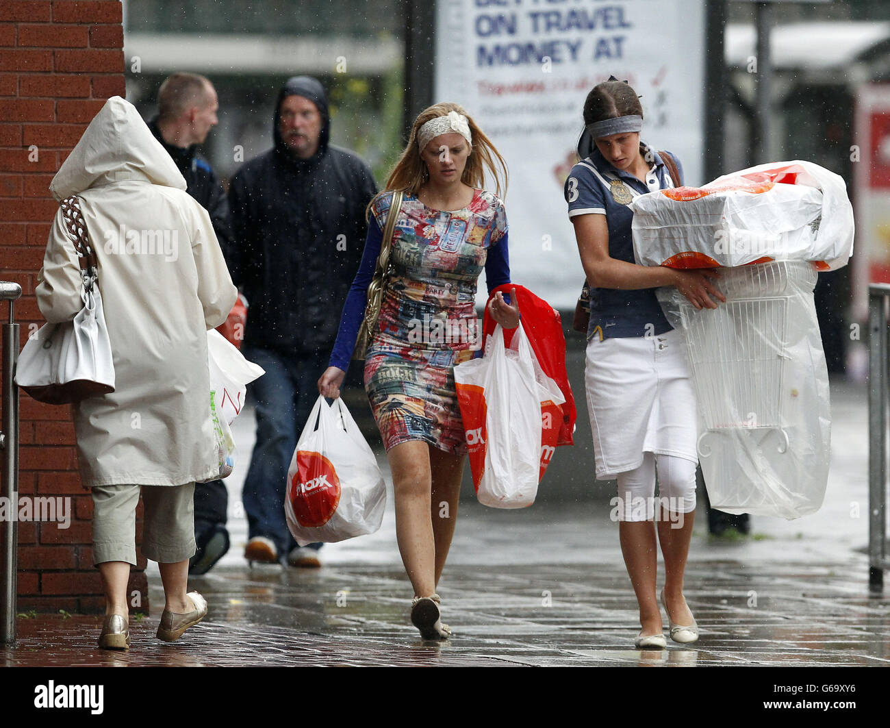 Zwei Mädchen tragen ihre Einkäufe im Regen in Stockport. Stockfoto