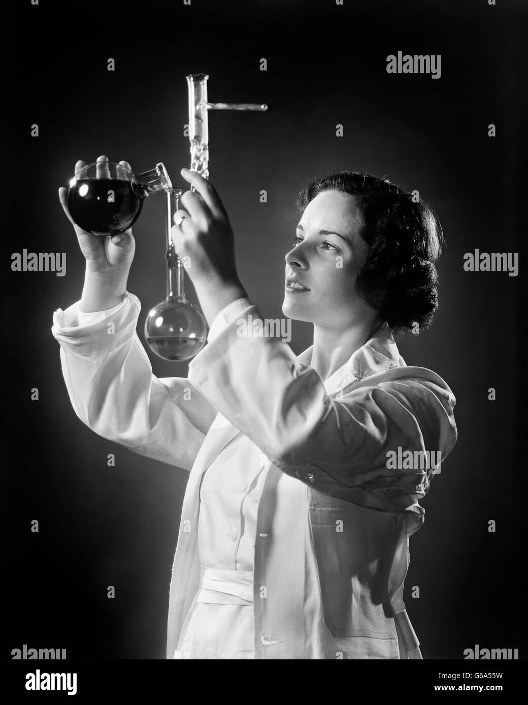 1930ER JAHREN WEIBLICHEN CHEMIKER WISSENSCHAFTLER GIEßEN FLÜSSIGKEIT IN EIN BECHERGLAS Stockfoto