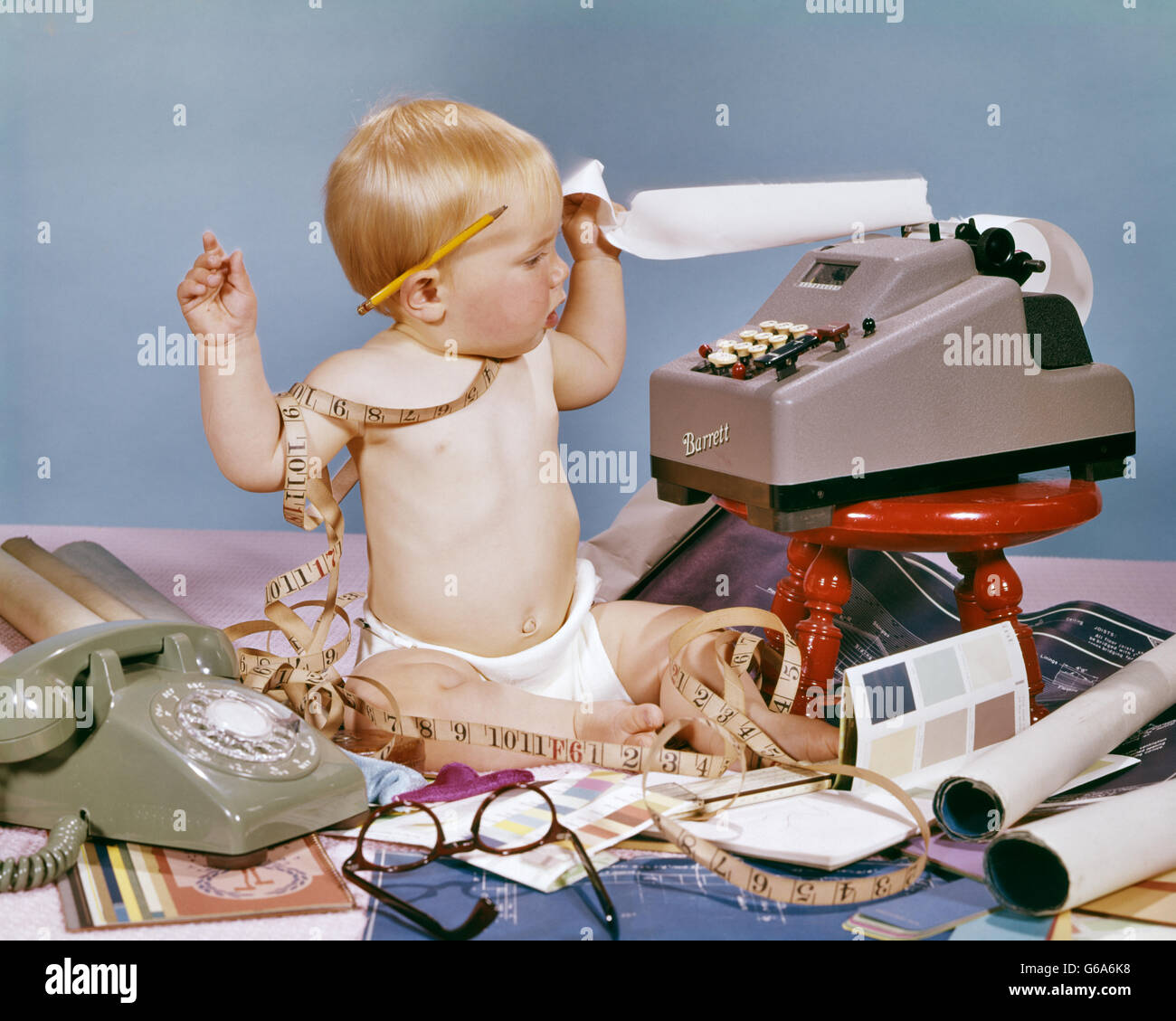 1960ER-JAHRE DESIGNER-BABY SITZEN WIRREN IN MAßBAND MIT DEM HINZUFÜGEN VON MASCHINE BLAUPAUSEN TELEFON FARBPROBEN Stockfoto