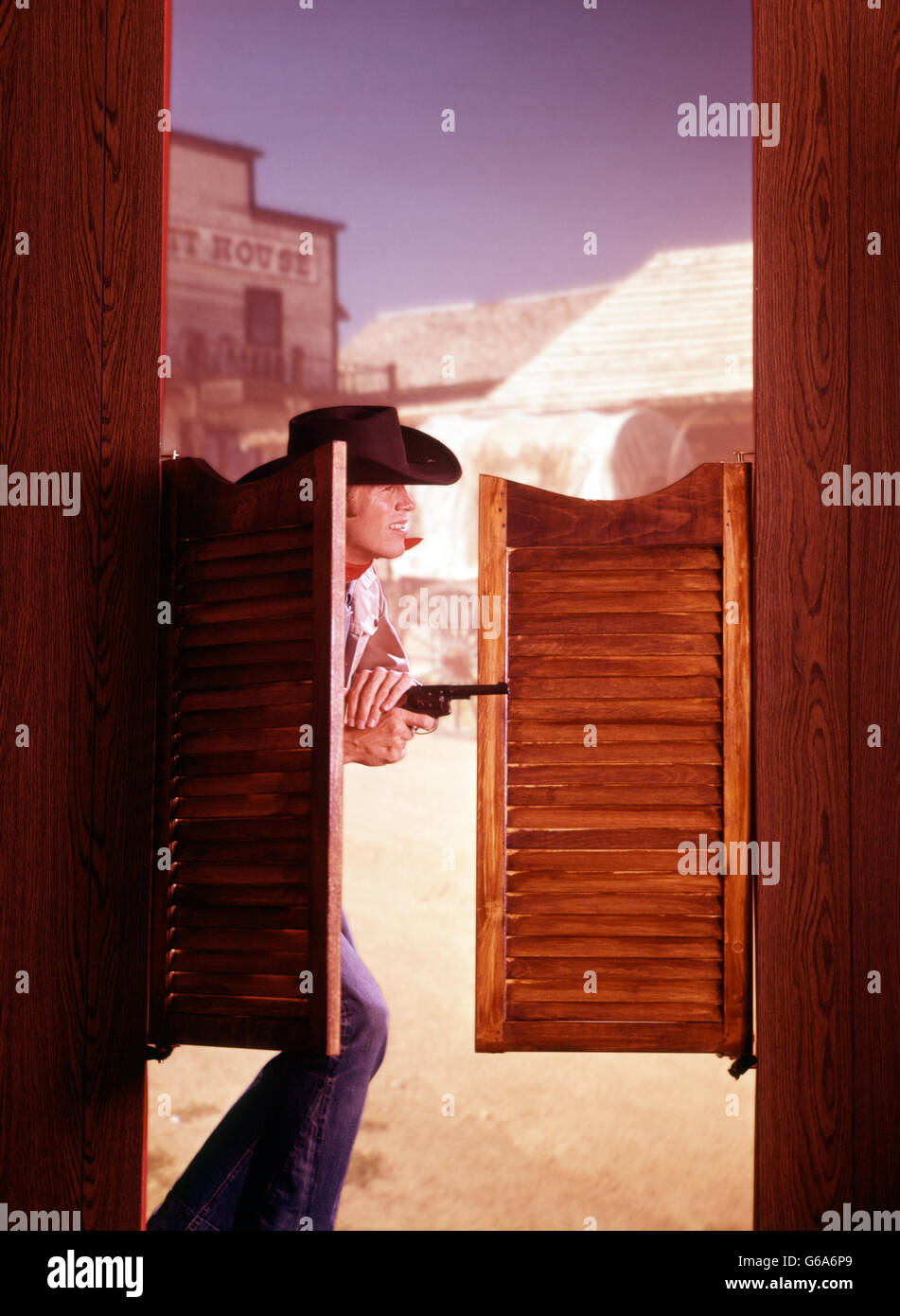 1960S 1970S WESTERN COWBOY MIT PISTOLE GEWEHR SCHWINGENDEN SALOONTÜREN DURCHKOMMEN Stockfoto