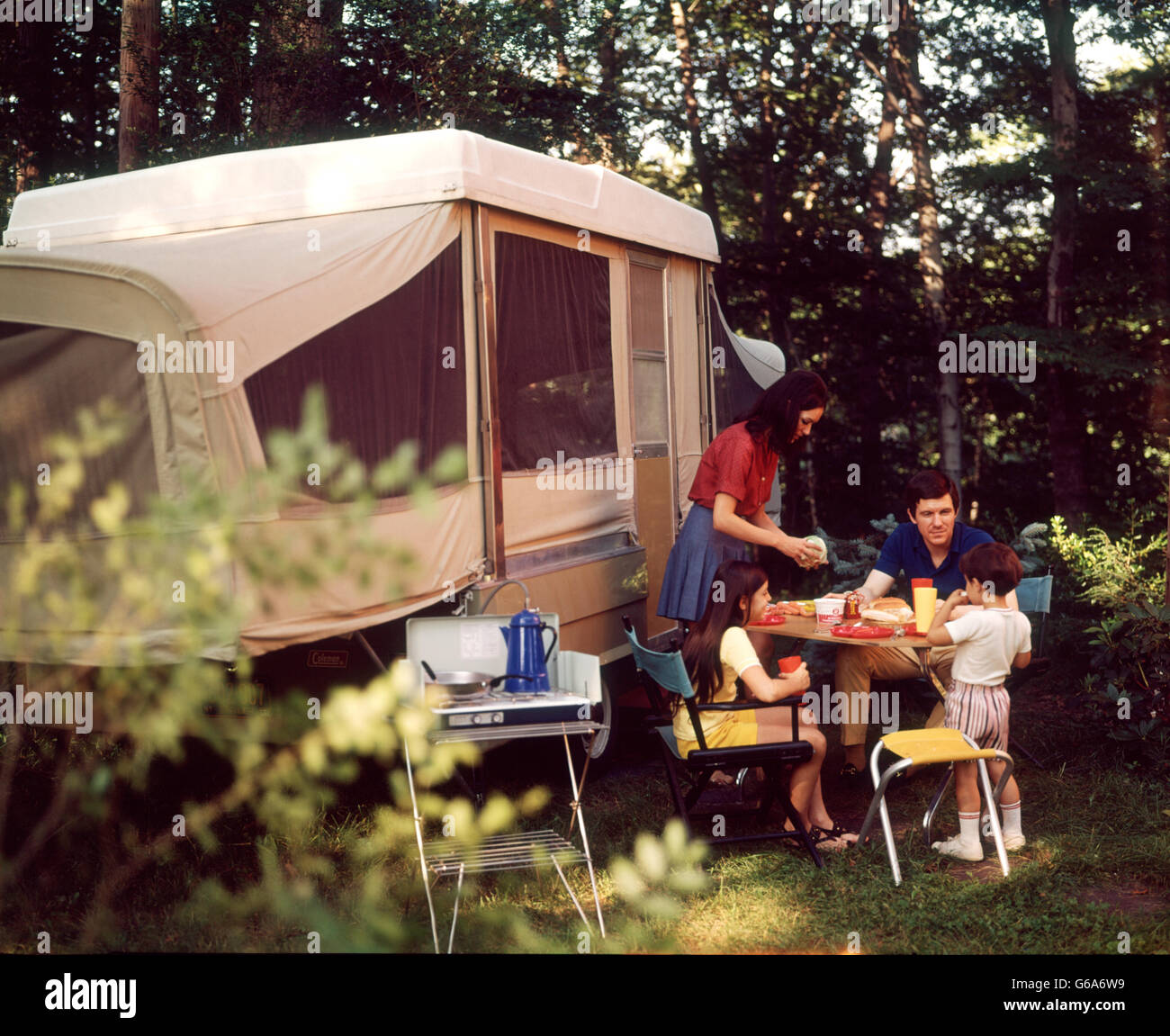 1970ER JAHREN MUTTER SERVIEREN FAMILIENESSEN VATER ZWEI KINDER AUßERHALB POP-UP-CAMPER Stockfoto