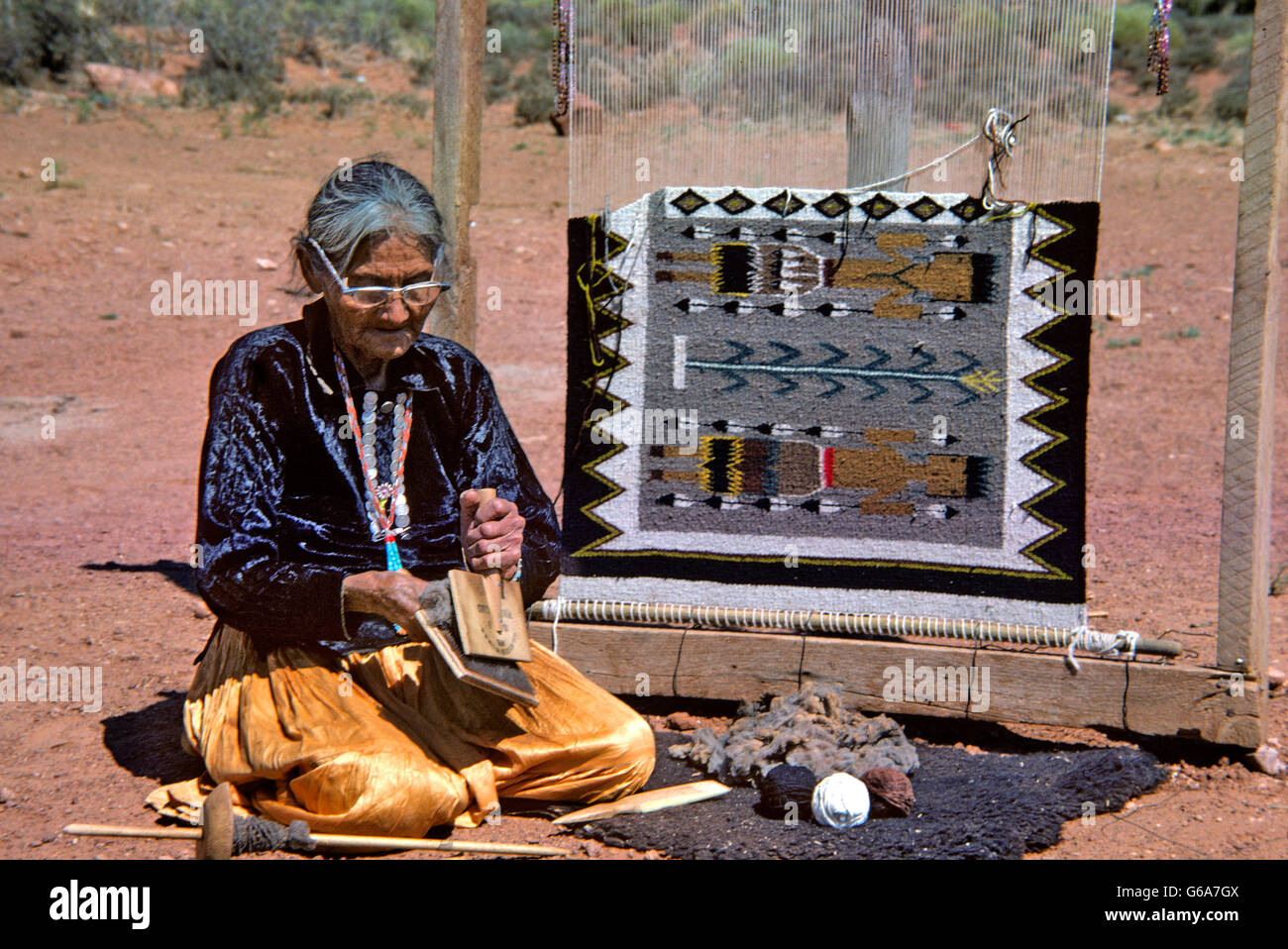 1970ER JAHRE SENIOR NAVAJO FRAU WEBEREI TEPPICH KARDIEREN WOLLE Stockfoto