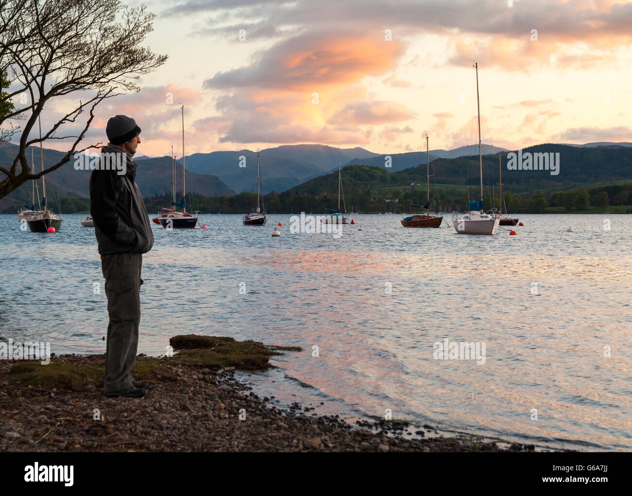 Ältere männliche Wanderer Blick auf Ullswater bei Sonnenuntergang. Pooley Bridge, Nationalpark Lake District, Cumbria, England, UK Stockfoto