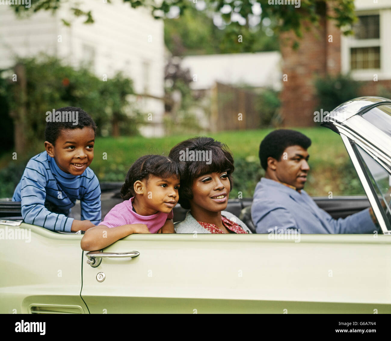 1970ER JAHRE AFRIKANISCHER AMERIKANER VIERKÖPFIGE FAMILIE REITEN IM CABRIO AUTO VATER MUTTER SOHN TOCHTER Stockfoto