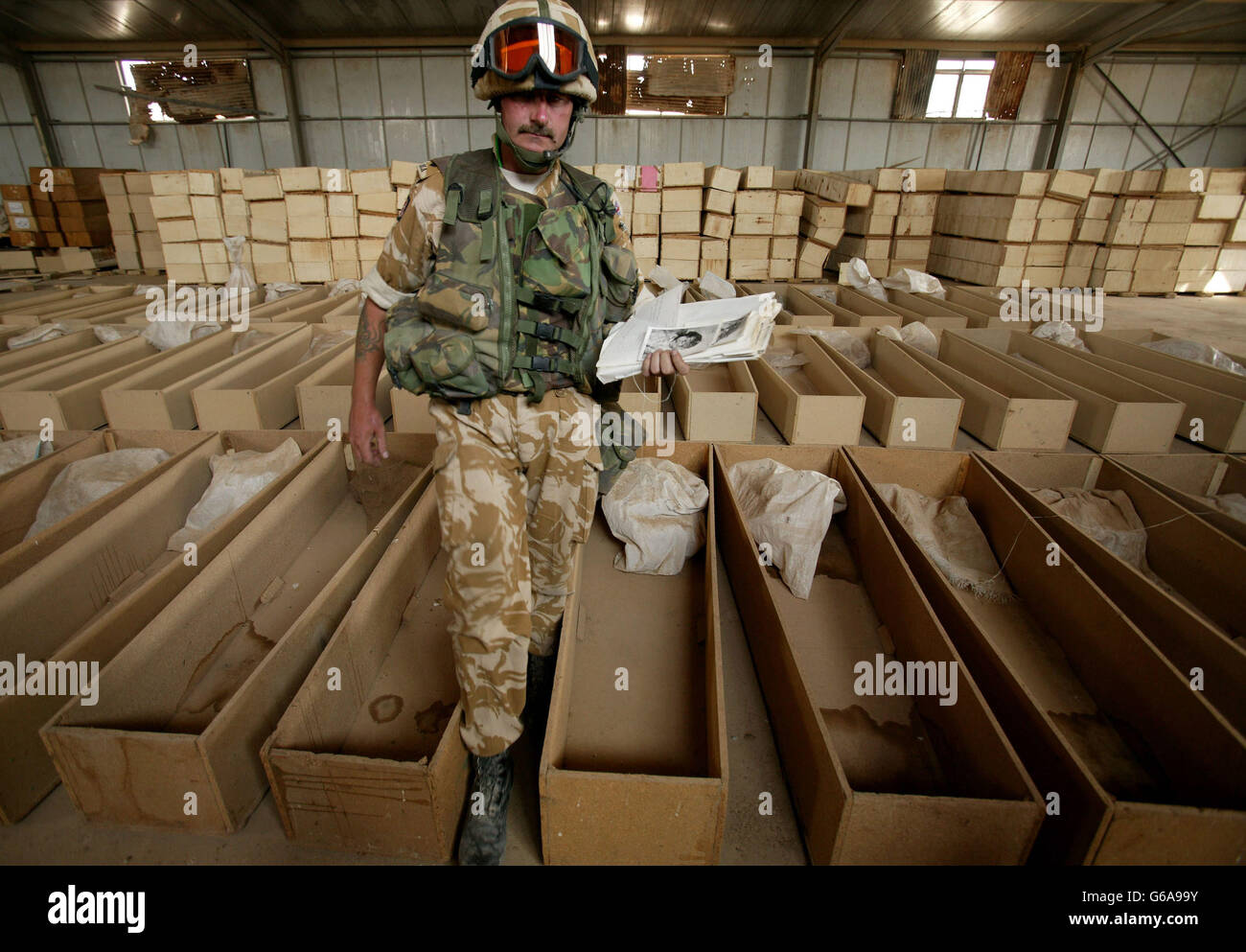 Ein Soldat hält ein Buch, das die Leichen von Irakern zeigt, die zusammen mit menschlichen Überresten und Särgen auf einer verlassenen irakischen Basis in der Nähe von Basra entdeckt wurden. Hunderte von menschlichen Überresten wurden in einer provisorischen Leichenhalle von britischen Soldaten im Südirak entdeckt. Dan Chung / Guardian / MOD Pool. *... Die Schädel, Knochenbündel in Streifen von Militäruniform, wurden in Plastiktüten und entsiegelten Hardboard-Särgen in einer verlassenen irakischen Militärbasis am Stadtrand von Al Zubayr abgeladen. Es war unmöglich zu sagen, wie lange die Überreste dort gelegen hatten, aber die grimmige Entdeckung wird jetzt sein Stockfoto