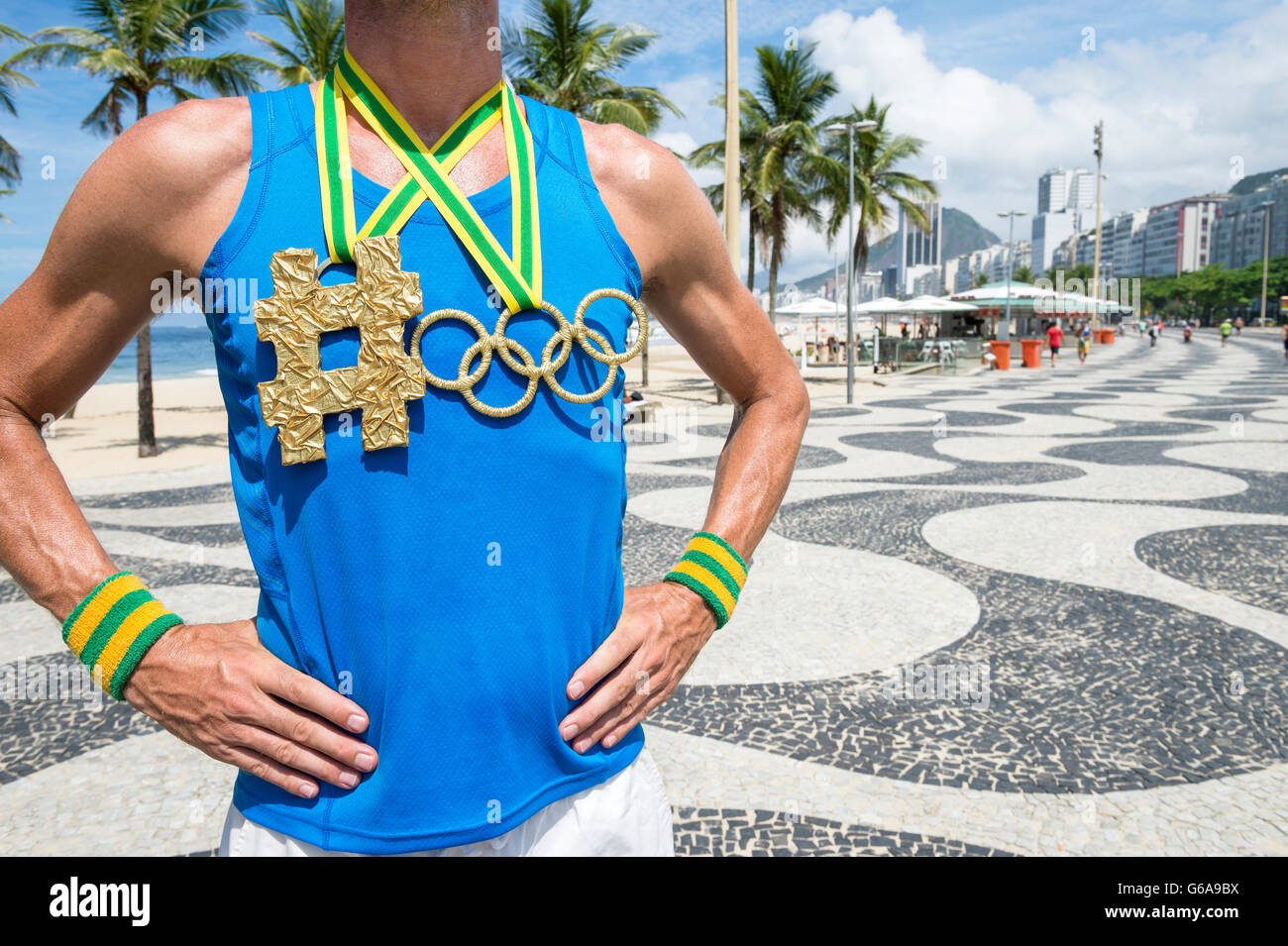 RIO DE JANEIRO - 10. März 2016: Athlet steht mit Olympischen Ringen gold Medaille hängen neben Hashtag am Strand der Copacabana. Stockfoto