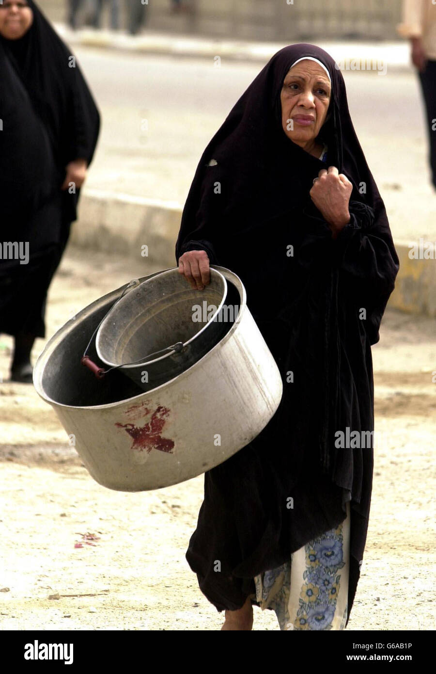 Eine Frau geht in die irakische Stadt Basra, um Wasser zu sammeln. Stockfoto