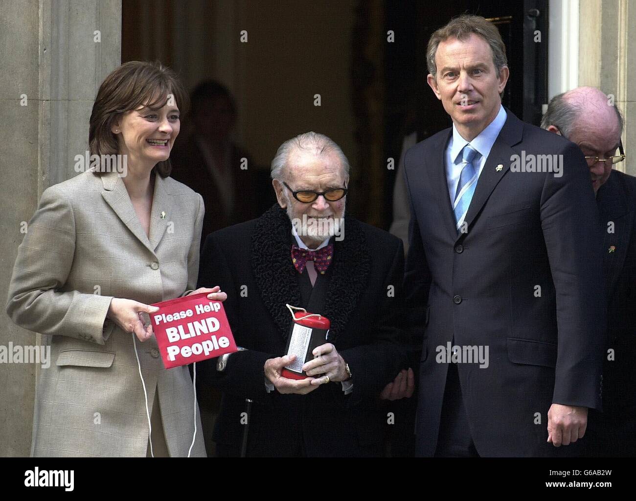 Der britische Premierminister Tony Blair (rechts) und seine Frau Cherie helfen mit einer Spende, den Greater London Fund für den Appell zum Geranium-Tag der Blinden zu starten, der die Downing Street Nr. 10 mit Sir John Mills, dem Vizepräsidenten der GLFD, übertraf. Stockfoto