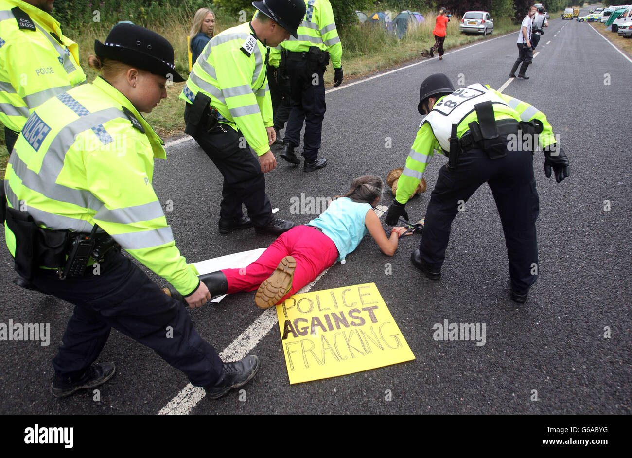 Eine Frau fällt herüber, als Demonstranten versuchen, Fahrzeuge zu verlangsamen, die auf dem Fracking-Gelände von Balcombe in West Sussex ankommen, da das Energieunternehmen Cuadrilla im Vorfeld von Explorationsbohrungen auf dem englischen Land begonnen hat, Geräte zu testen, da die Anti-Fracking-Proteste vor Ort an einem neunten Tag antraten. Stockfoto