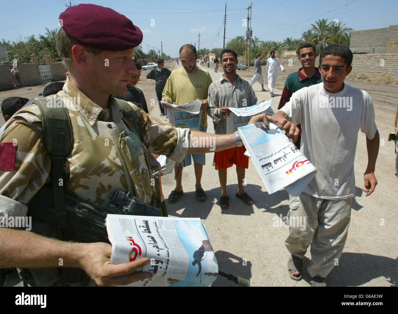 Ein Offizier des 1. Bataillons das Parachute-Regiment verteilt Zeitungen an irakische Menschen in und um al Qurna. *..die tägliche arabisch-sprachige Zeitung wurde von den Koalitionstruppen produziert und zeigte ein großes Bild von Saddam Husseins Statue in Bagdad, die gestürzt wurde. Stockfoto