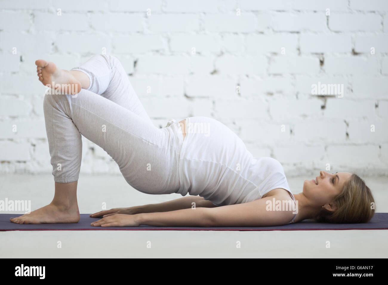 Schwangerschaft-Yoga und Fitness-Konzept. Schöne junge schwangere Yoga Modell indoor erarbeiten. Schwangere happy Fitness person Stockfoto
