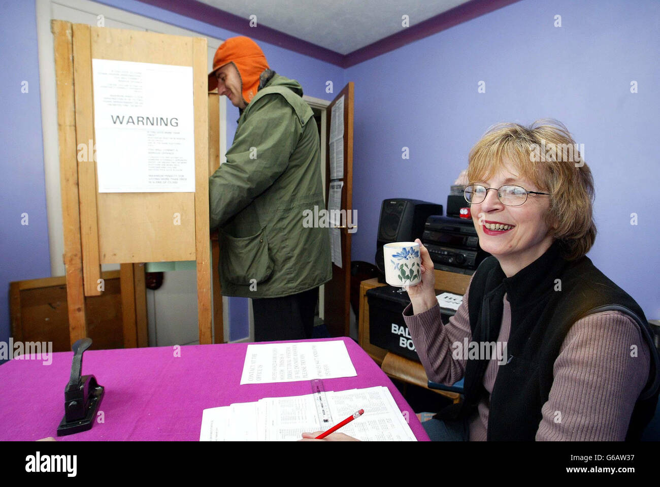 Poll Clerk Caroline Bishop hat eine Tasse Tee an einer Polling Station in Chettisham, Cambridgeshire, im Schlafzimmer eines Familienbungalows. * Frau Carmelia Bond, 54, bot dem Bezirksrat von East Cambridgeshire vor fast 25 Jahren, nachdem das Dorfhaus geschlossen wurde, das Schlafzimmer ihrer Söhne als Wahllokal an. Sie zog sein Bett und den Tank mit seiner Haustier-Maus Mary in die Lounge bereit für die Wahlkabine installiert werden, aber der Fernseher blieb im Schlafzimmer, wie einige Wähler gerne beobachten, während sie warten, um an der Reihe. Mehr als 30 Millionen Wähler wählen ihre Vertreter auf der schottischen Stockfoto