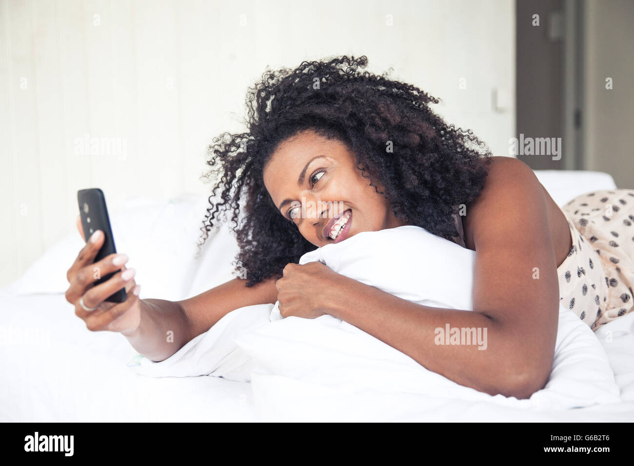 Frau mit Handy auf Bett Stockfoto