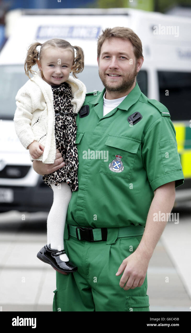 Die dreijährige Casey McLean mit den Sanitätern Andy Houston, einer der Sanitäter, die ihr das Leben rettete, nachdem sie in Glasgow einen Herz-/Atemstillstand erlitten hatte. Stockfoto