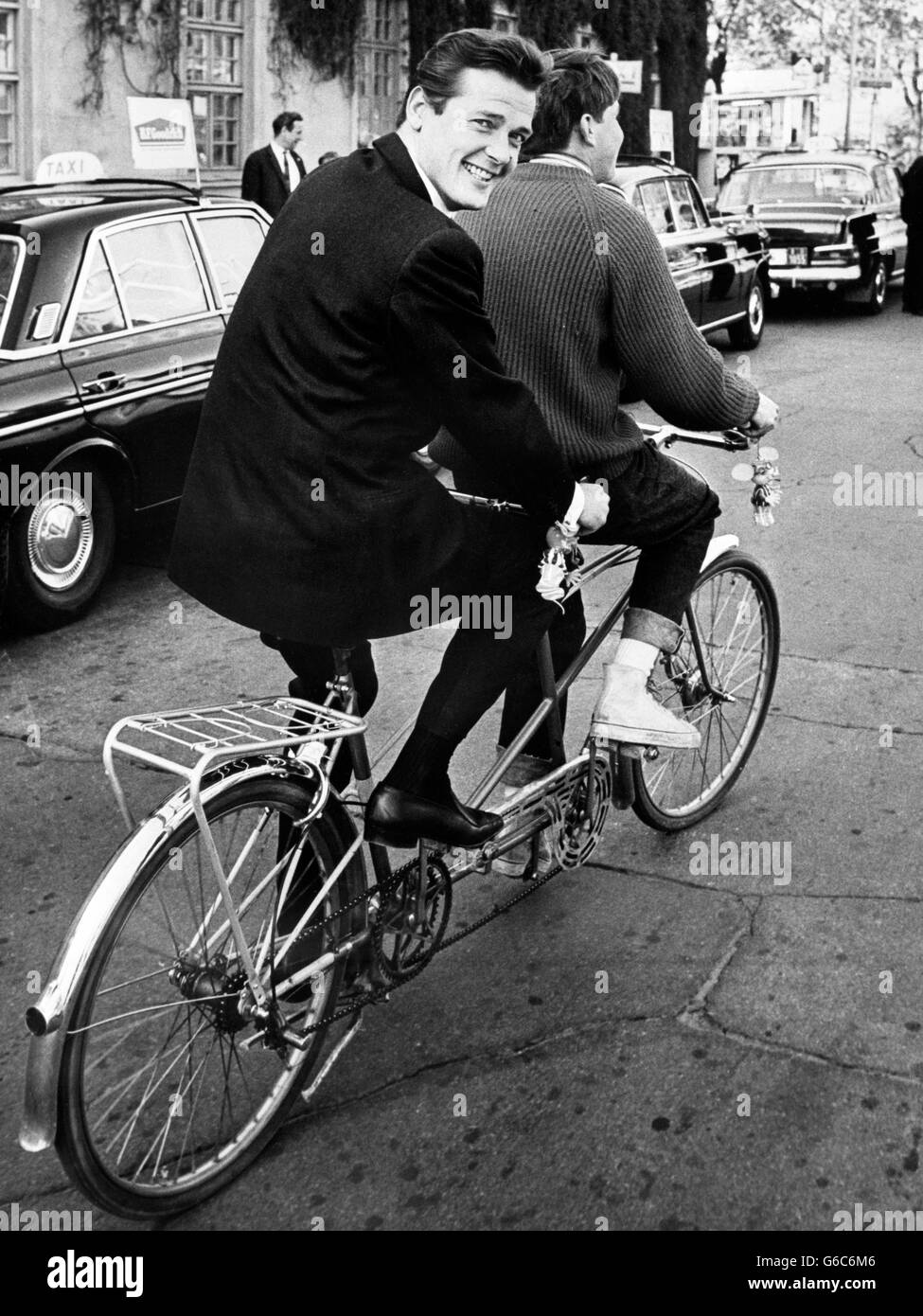 Unterhaltung - Roger Moore - Stockholm, Schweden. Roger Moore fährt auf dem Rücken eines Tandemfahrrads durch die Straßen Stockholms in Schweden. Stockfoto