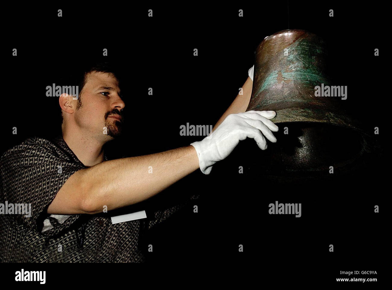 Tom Zaller, Produktionsleiter der Titanic Artifact Exhibition im Science Museum im Westen Londons, stellt die Glocke vom Krähennest der Titanic auf. Die Schiffsglocke, die kurz vor dem Anschlagen eines Eisbergs geläutet wurde, *..und ist Teil der Ausstellung, die am 16. Mai für die Öffentlichkeit zugänglich ist. Stockfoto