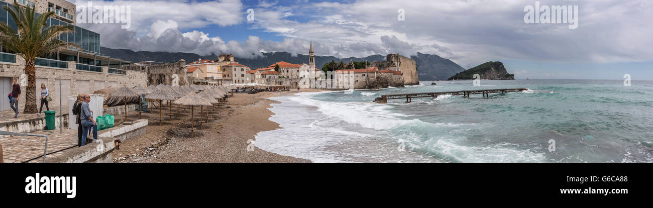 Die alte befestigte Stadt Budva erschossen vom Strand entfernt. Zeigt das Adriatische Meer, ein bewölkter Himmel & Neuentwicklung Hotel auf der linken Seite Stockfoto